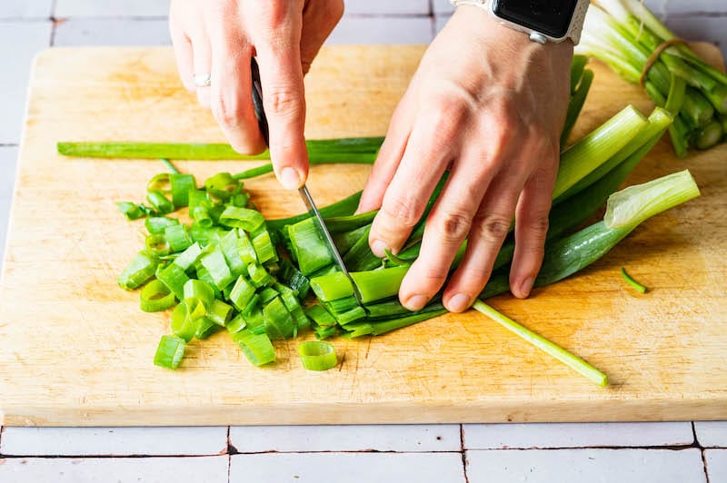 Spring onions are being cut into rings.