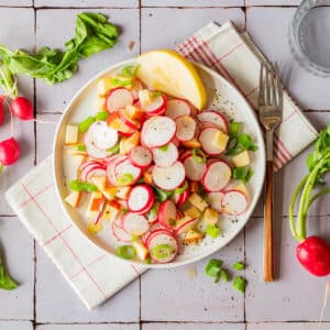 Radish Apple Salad with scallions on a white plate.