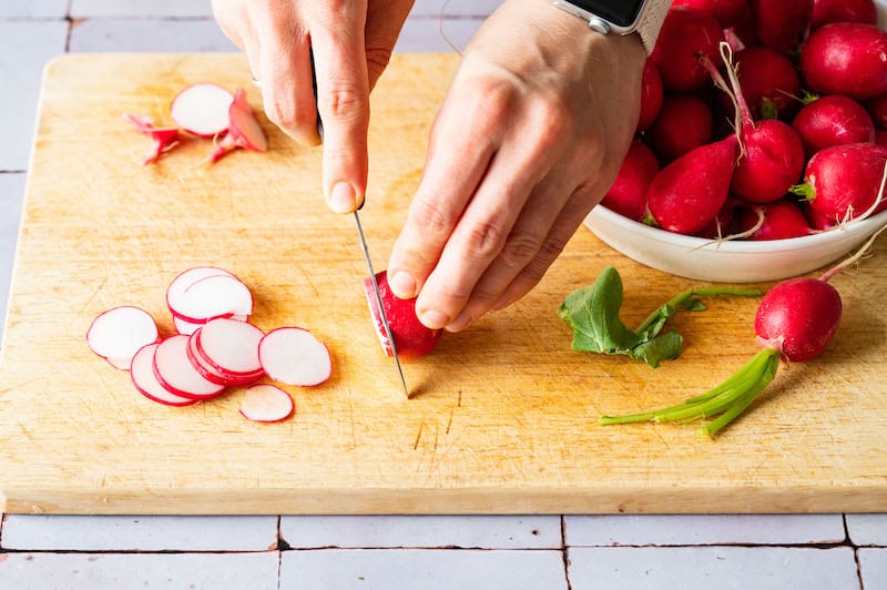 Radish being cut into thin slices.