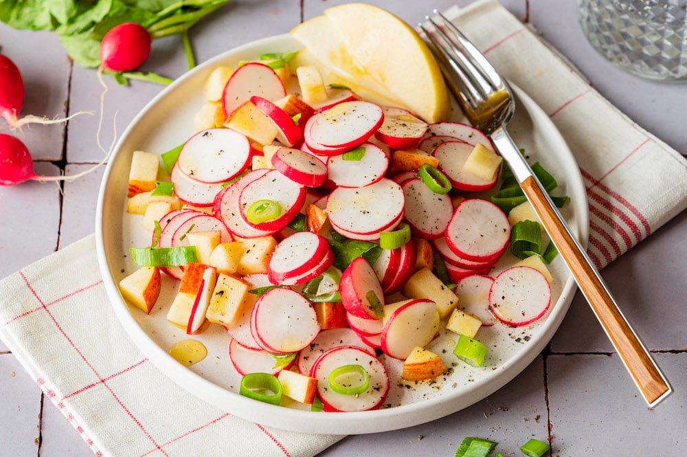 Apple radish salad with spring onions on a plate.