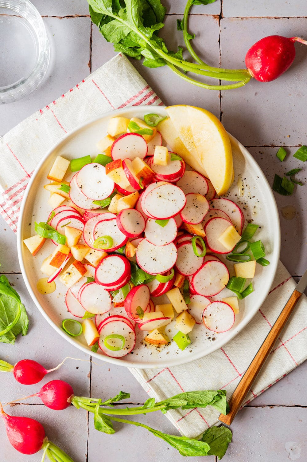 Radish and apple salad with scallions on a plate.